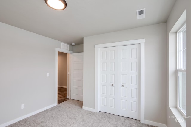 unfurnished bedroom with a closet and light carpet