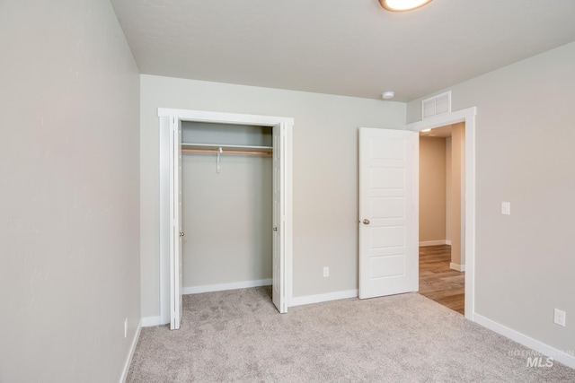 unfurnished bedroom featuring a closet and light carpet