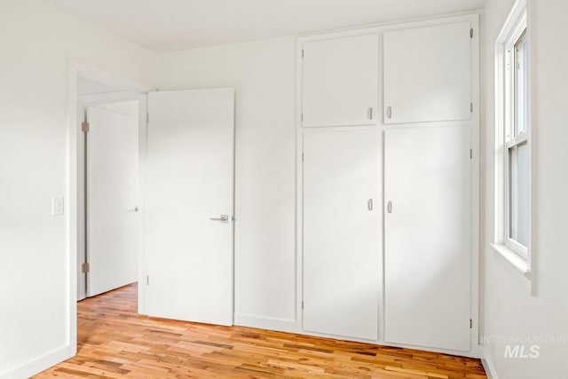 unfurnished bedroom with a closet and light hardwood / wood-style floors