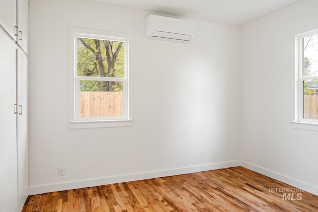 unfurnished room with a wall unit AC and light wood-type flooring