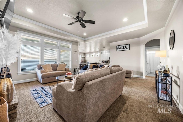 living room featuring a tray ceiling, a textured ceiling, ceiling fan, and carpet flooring