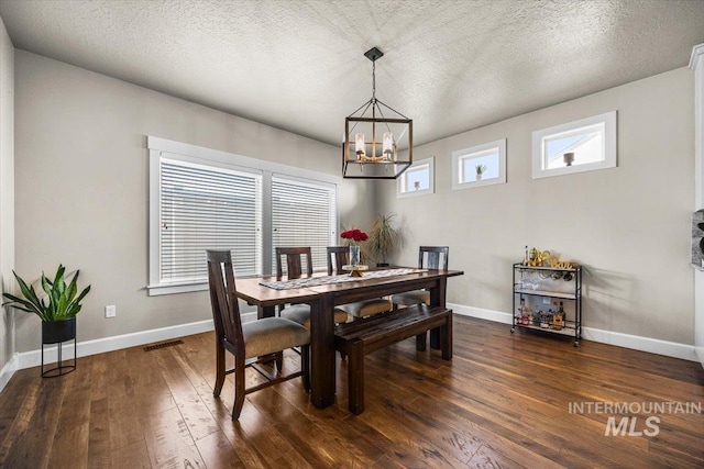 dining area featuring dark hardwood / wood-style floors, a textured ceiling, and a notable chandelier