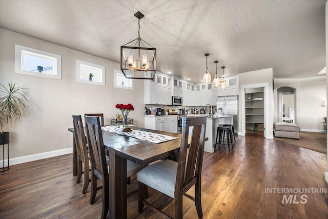 dining space featuring an inviting chandelier, built in shelves, dark wood-type flooring, and a textured ceiling