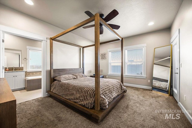 carpeted bedroom featuring sink, ensuite bath, and ceiling fan