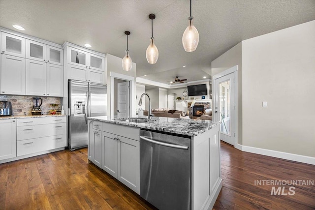 kitchen featuring sink, white cabinetry, hanging light fixtures, stainless steel appliances, and an island with sink