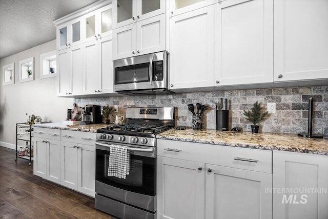 kitchen featuring dark hardwood / wood-style flooring, light stone countertops, stainless steel appliances, and white cabinets