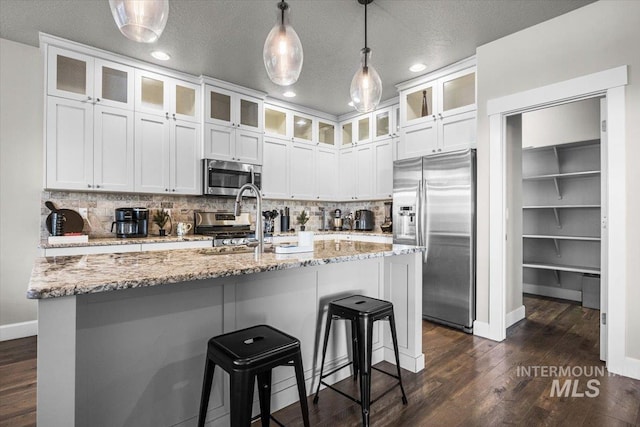 kitchen featuring tasteful backsplash, appliances with stainless steel finishes, a center island with sink, and white cabinets