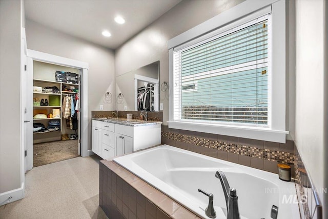 bathroom with vanity and tiled bath