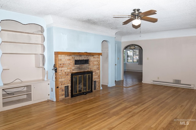 286 SW 3rd Ave, Ontario, OR 97914 - unfurnished living room with baseboard heating, a textured ceiling, ceiling fan, light wood-type flooring, and a brick fireplace