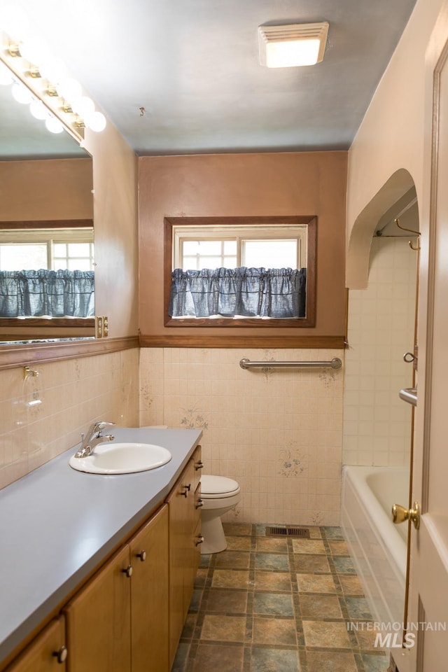 286 SW 3rd Ave, Ontario, OR 97914 - bathroom with tile walls, plenty of natural light, vanity, toilet, and a wainscoted wall