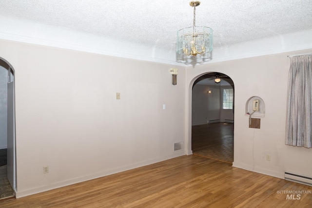 286 SW 3rd Ave, Ontario, OR 97914 - empty room featuring arched walkways, light wood-style flooring, a baseboard heating unit, and a textured ceiling