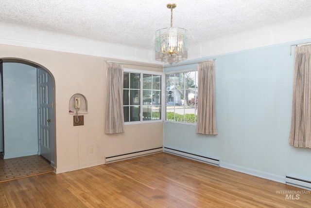 286 SW 3rd Ave, Ontario, OR 97914 - unfurnished room with wood finished floors, a textured ceiling, a baseboard heating unit, a chandelier, and arched walkways