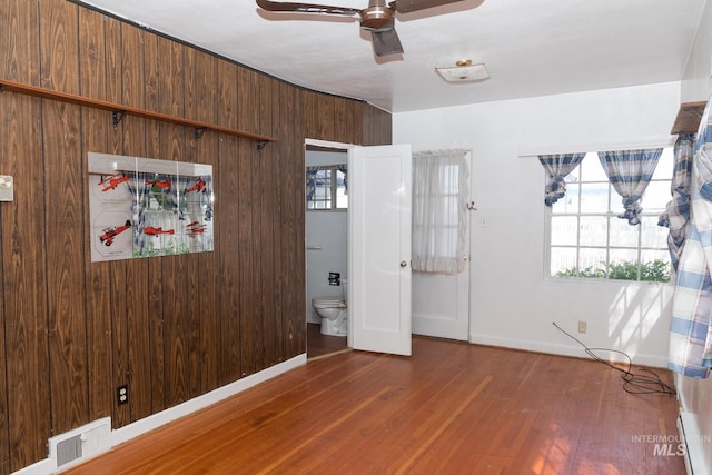 286 SW 3rd Ave, Ontario, OR 97914 - unfurnished bedroom featuring wood finished floors, baseboards, wooden walls, and a ceiling fan