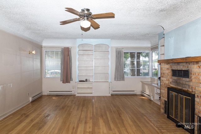 286 SW 3rd Ave, Ontario, OR 97914 - unfurnished living room featuring baseboard heating, a brick fireplace, a textured ceiling, wood-type flooring, and crown molding