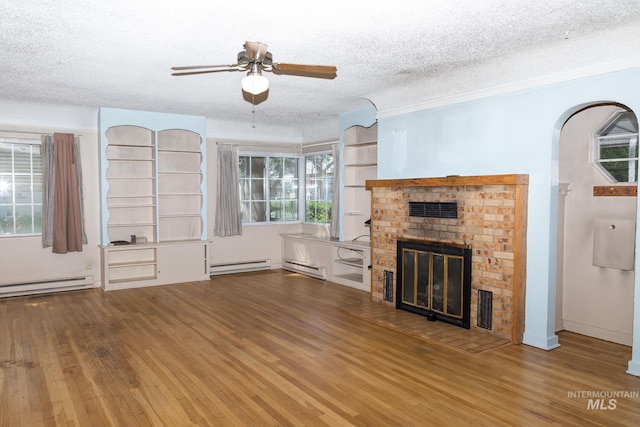 286 SW 3rd Ave, Ontario, OR 97914 - unfurnished living room featuring baseboard heating, wood finished floors, ceiling fan, a brick fireplace, and a textured ceiling