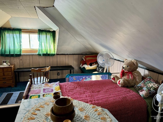 bedroom with vaulted ceiling, carpet flooring, and wooden walls