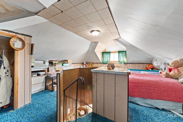 carpeted bedroom with lofted ceiling and wood walls