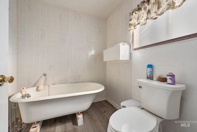 bathroom featuring tile walls, hardwood / wood-style flooring, a tub, and toilet