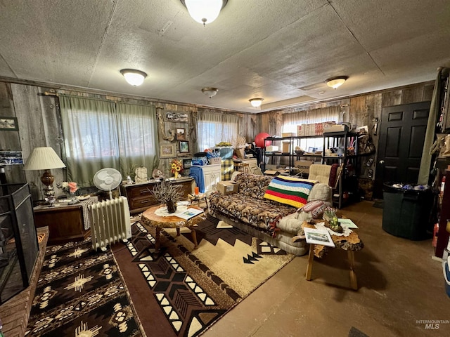 miscellaneous room featuring concrete flooring, a textured ceiling, and wood walls