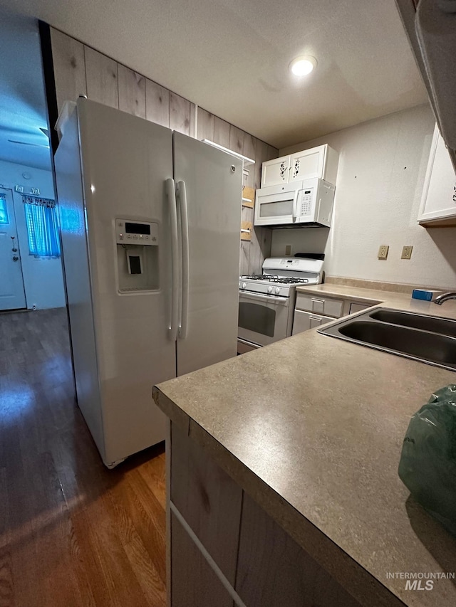 kitchen featuring white appliances, white cabinetry, dark wood-type flooring, and sink