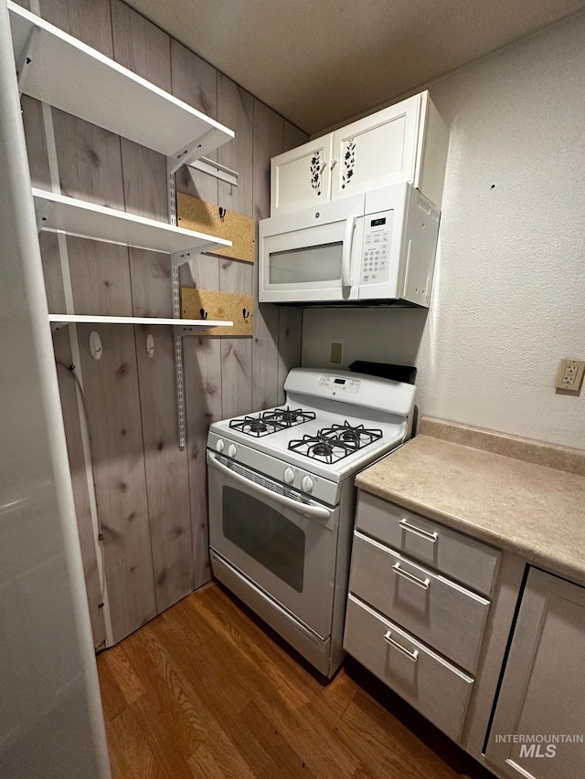 kitchen featuring white cabinetry, dark hardwood / wood-style floors, and white appliances