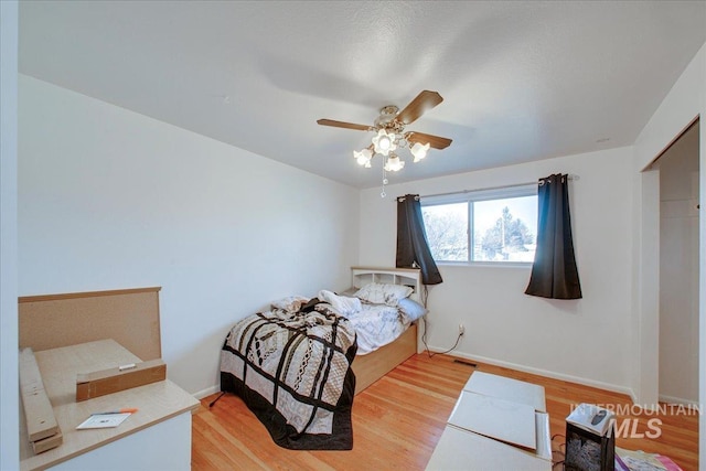 bedroom featuring light wood-style flooring, baseboards, and ceiling fan