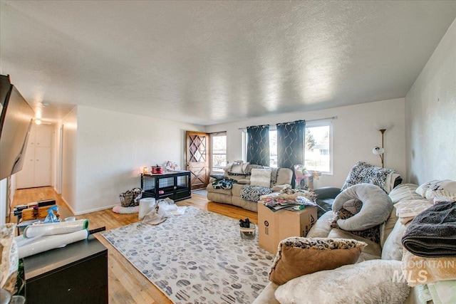 living area with light wood-style floors, baseboards, and a textured ceiling