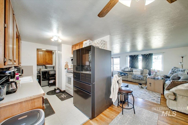 kitchen featuring brown cabinetry, open floor plan, freestanding refrigerator, and ceiling fan