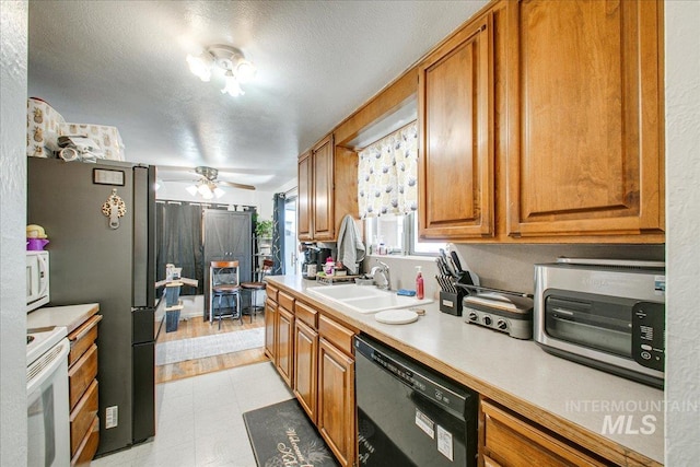 kitchen featuring a ceiling fan, a sink, white appliances, brown cabinetry, and light countertops