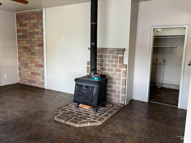 interior details featuring ceiling fan and a wood stove