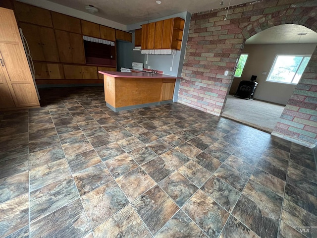 kitchen featuring dark carpet, wood walls, kitchen peninsula, a wood stove, and a breakfast bar area