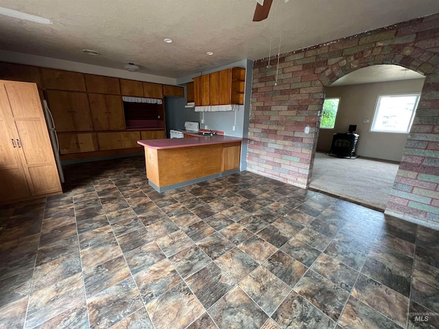 kitchen featuring dark colored carpet, a wood stove, kitchen peninsula, ceiling fan, and white range with electric cooktop