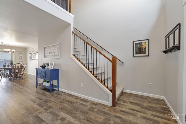 stairs with hardwood / wood-style flooring and a notable chandelier