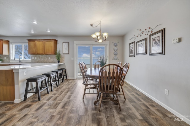 dining area with plenty of natural light, dark hardwood / wood-style flooring, a textured ceiling, and a notable chandelier