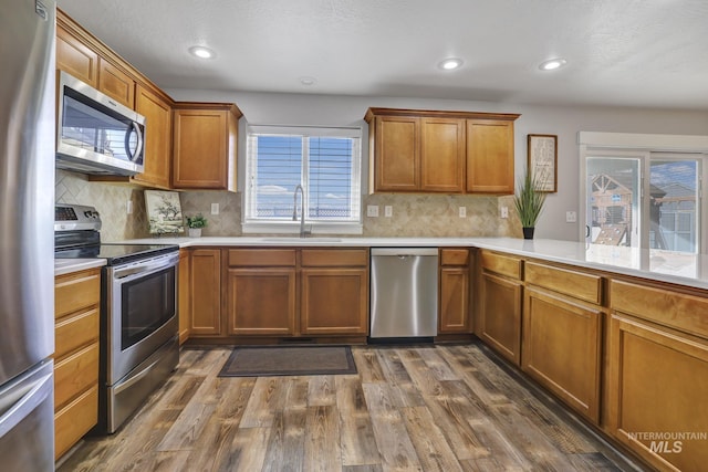 kitchen with tasteful backsplash, appliances with stainless steel finishes, sink, and dark hardwood / wood-style flooring