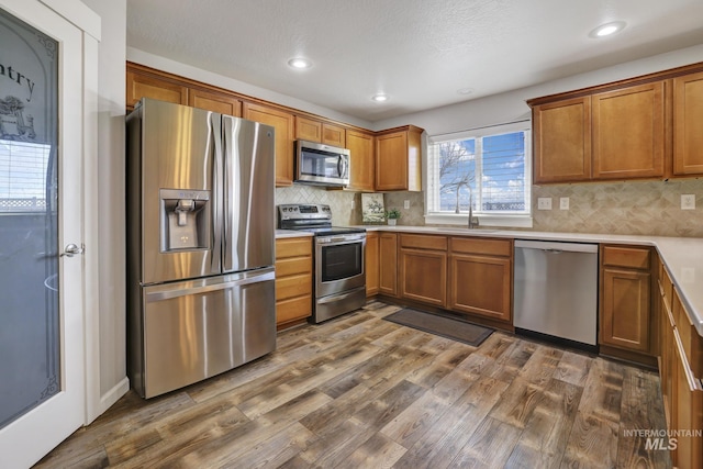 kitchen featuring stainless steel appliances, dark hardwood / wood-style floors, sink, and decorative backsplash