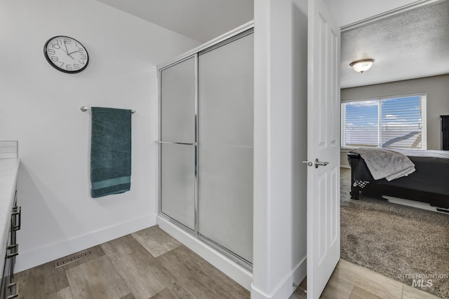 bathroom featuring vanity, a shower with shower door, and a textured ceiling