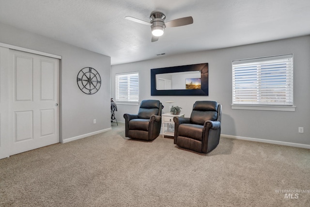 living area with light carpet and ceiling fan