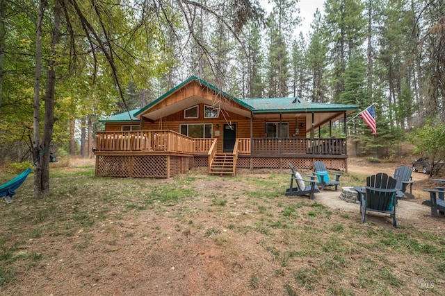 rear view of house featuring log veneer siding, a wooden deck, metal roof, and an outdoor fire pit