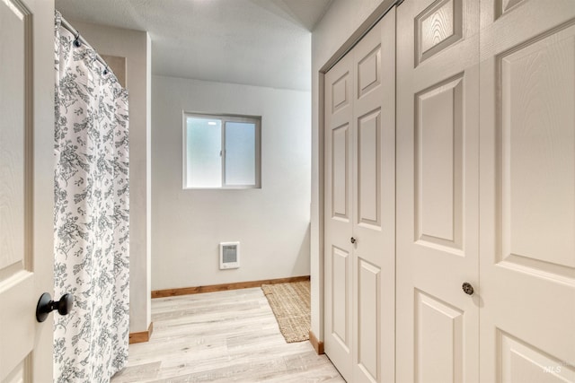 hall with visible vents, baseboards, and light wood-style floors