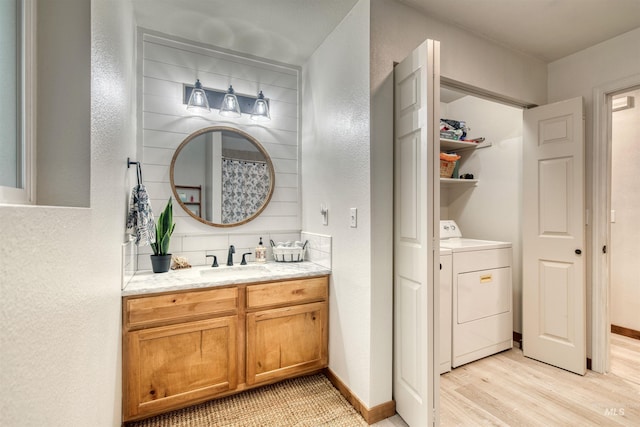 full bathroom with vanity, wood finished floors, baseboards, and a textured wall