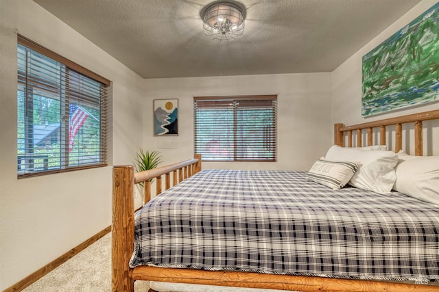 carpeted bedroom featuring multiple windows, baseboards, and a textured ceiling