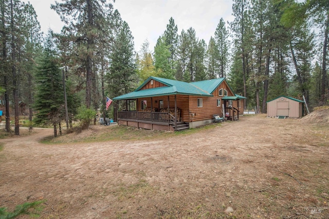 view of front of house with an outbuilding, a porch, a storage unit, and metal roof