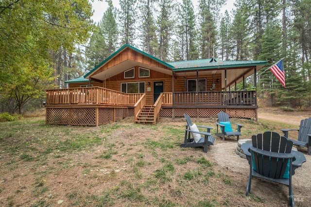 back of house with metal roof, a fire pit, a deck, and faux log siding