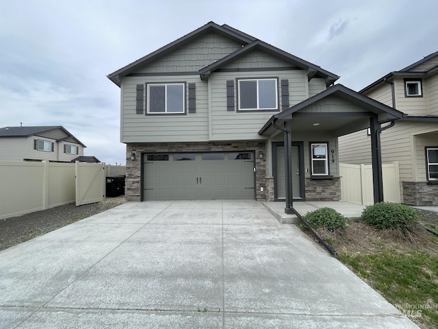 view of front of home featuring a garage, stone siding, fence, driveway, and a gate