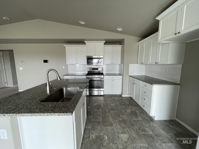 kitchen featuring stainless steel appliances, a sink, vaulted ceiling, tasteful backsplash, and white cabinetry