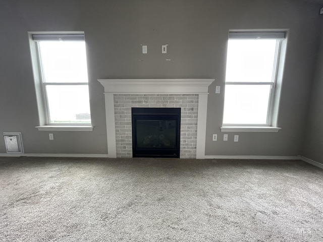 unfurnished living room featuring carpet floors, a fireplace, and plenty of natural light