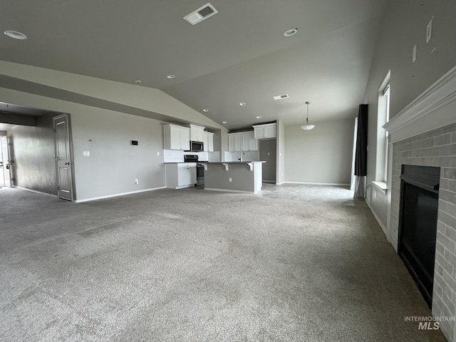 unfurnished living room with vaulted ceiling, a fireplace, light colored carpet, baseboards, and a sink