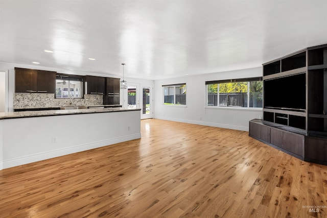 unfurnished living room featuring light wood-style floors, a sink, baseboards, and recessed lighting
