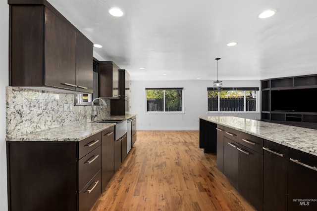 kitchen with a sink, baseboards, recessed lighting, decorative backsplash, and light wood-style flooring